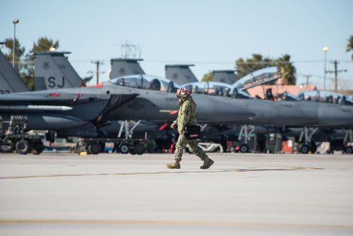 Maintainers from the U.S. Navy walk by F-15E Strike Eagles on the way to their jets at Nellis Air Force Base, Nev., Jan. 25, 2016, during Red Flag 16-1. Four branches of the military and coalition partners participate in Red Flag. The training is conducted to familiarize forces for working together in future operations.