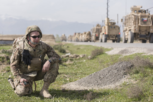An Airman crouches by the road in Khanjar Khel, Parwan Province, Afghanistan, after making a call on his radio, March 30, 2016. The F-16 crashed after takeoff and the pilot safely ejected; since then, the base completed cleaning up the crash site. The cause of the accident is under investigation. (U.S. Air Force photo/Tech. Sgt. Robert Cloys)