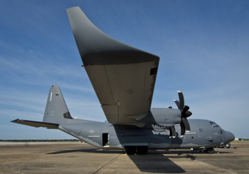 A modified MC-130J waits for its next mission as another C-130 lifts off above it at Eglin Air Force Base, Fla. The test aircraft has been fitted with vertical fins on each wing, called winglets.  The 413th Flight Test Squadron aircrew and engineers tested the modified aircraft over eight flights.  The goal of the tests was to collect data on possible fuel efficiency improvements and performance with the winglets and lift distribution control system installed.  (U.S. Air Force photo/Samuel King Jr.)