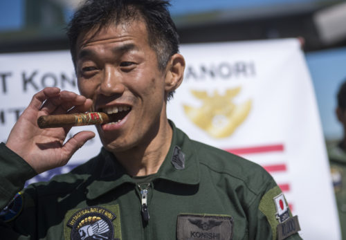 Japanese Air Defense Force Chief Master Sgt. Takanori Konishi, with the 401st Squadron, 1st Tactical Airlift Wing in Japan tries a celebratory cigar after completing the milestone of 10,000 C-130 Hercules flight hours on June 15, 2016, at Joint Base Elmendorf-Richardson, Alaska. A rare milestone, Konishi has spent a little over 416 days flying in the C-130. (U.S. Air Force photo by Senior Airman James Richardson/Released)