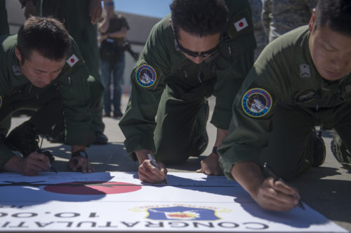 Japanese Air Defense Force Airmen with the 401st Squadron, 1st Tactical Airlift Wing in Japan, sign a banner for Chief Master Sgt. Takanori Konishi after he completed the milestone of 10,000 C-130 Hercules flight hours on June 15, 2016, at Joint Base Elmendorf-Richardson, Alaska. A rare milestone, Konishi has spent a little over 416 days flying in the C-130. (U.S. Air Force photo by Senior Airman James Richardson/Released)