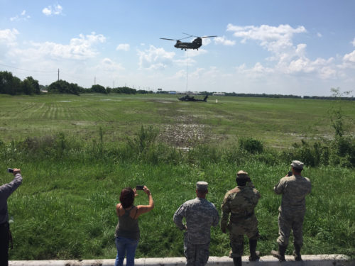 Texas Guardsmen and local Texans watch a CH-47 Chinook helicopter sling load an AH-64D Apache helicopter, September 1, 2016, following a precautionary landing in a rice paddy in Wallisville, Texas, near Houston, due to mechanical issues. Maintenance soldiers from the 1st Battalion, 149th Aviation Regiment (Attack Reconnaissance) waded through six-inch deep mud and worked in a heat index of more than 100 degrees, to ensure a safe and successful sling load recovery mission. (U.S. Army National Guard photo by Capt. Martha Nigrelle)
